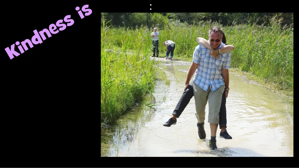 Kindness example slide pairs “Kindness is” with a man carrying another person on his back through water.