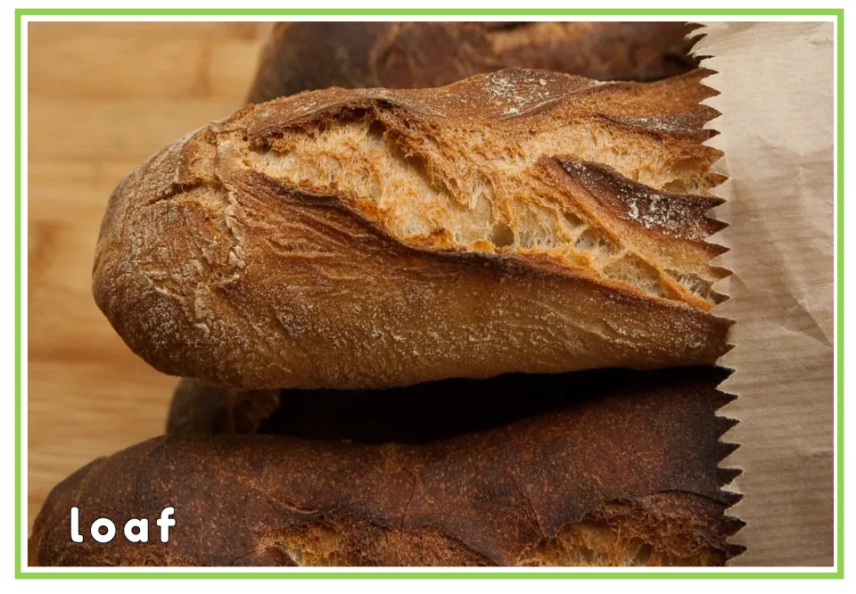 Loaf vocabulary card: the printed word loaf on a close-up of crusty baguettes, linking the written word to the picture