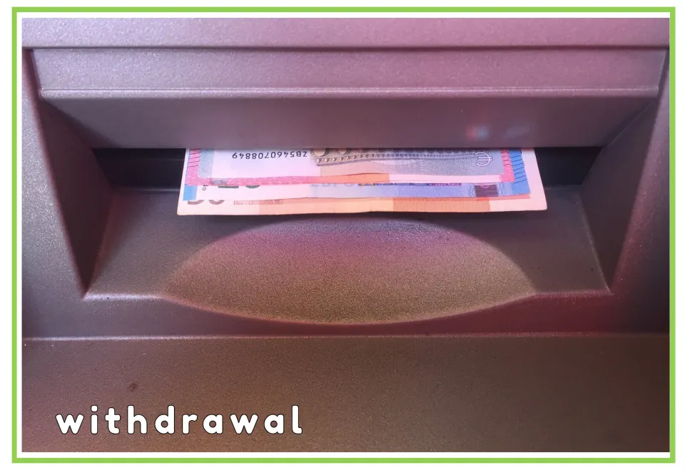 Withdrawal flashcard: banknotes sticking out of a cash machine slot with the printed word withdrawal for sign practice