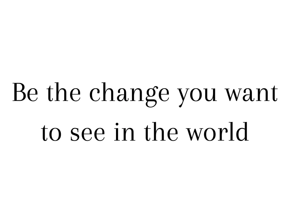 Citizenship quote sign: "Be the change you want to see in the world" in light black serif type on two lines