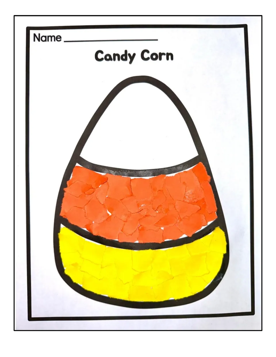 Finished candy corn sample: torn orange and yellow paper pieces glued inside the outline, leaving the tip white