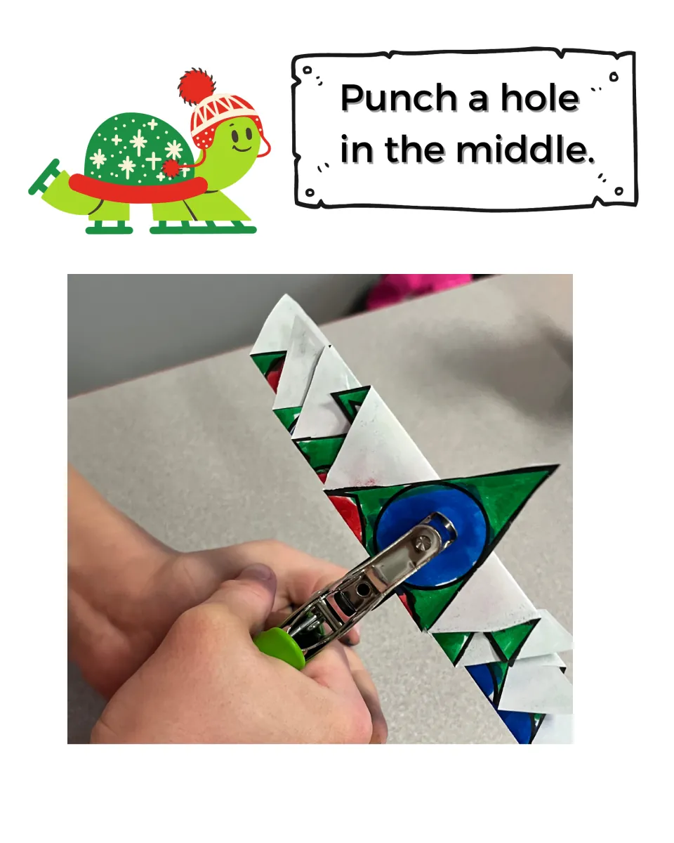 Punch a hole in the middle: photo of a hole punch going through the center of a folded, colored paper tree