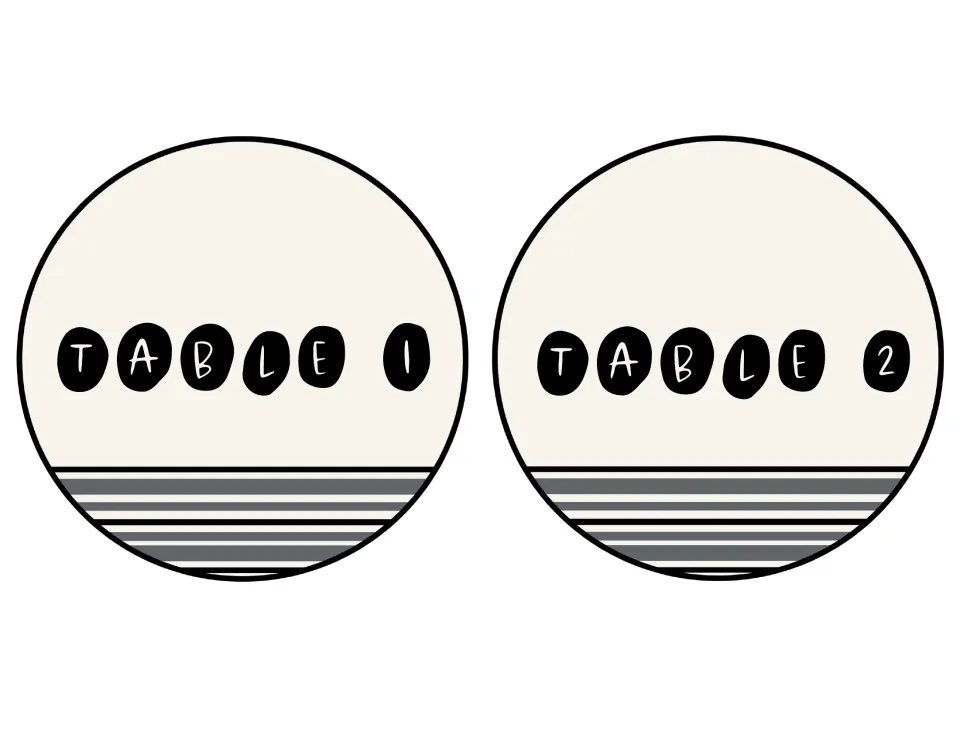Round table signs for Table 1 and Table 2: cream circles with black pebble letters and gray stripes across the bottom