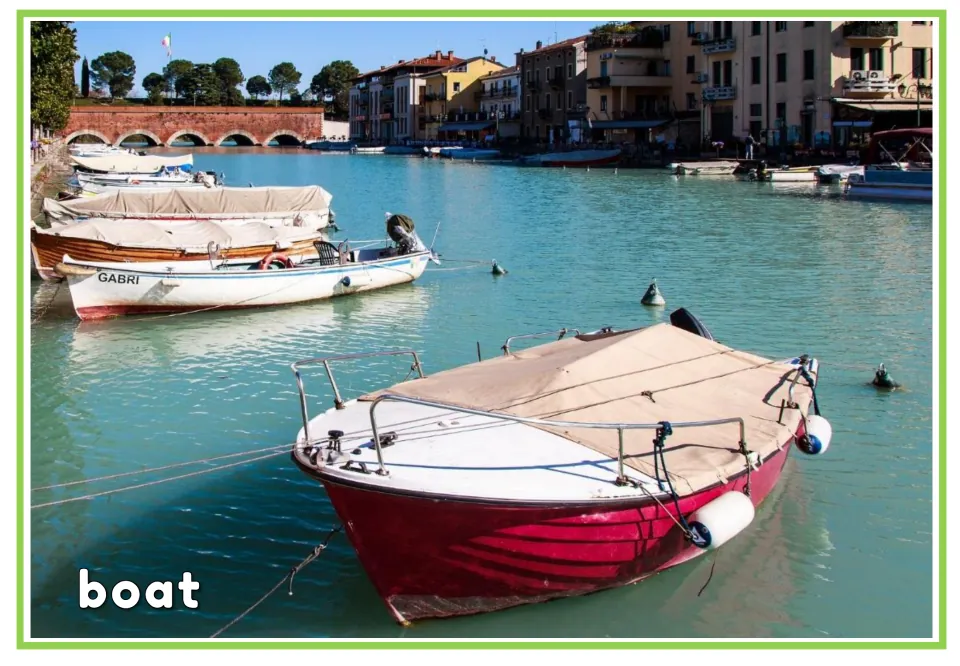 Labeled watercraft vocabulary flashcard showing a red boat moored in a harbor with the English word 'boat'