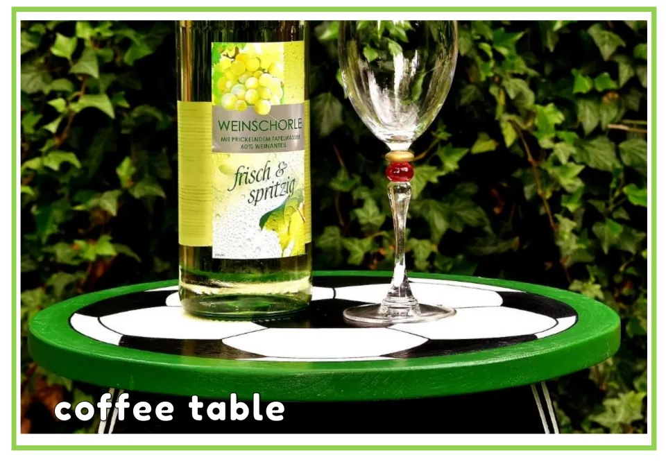 Labeled garden vocabulary flashcard showing a round green table outdoors with the words 'coffee table'