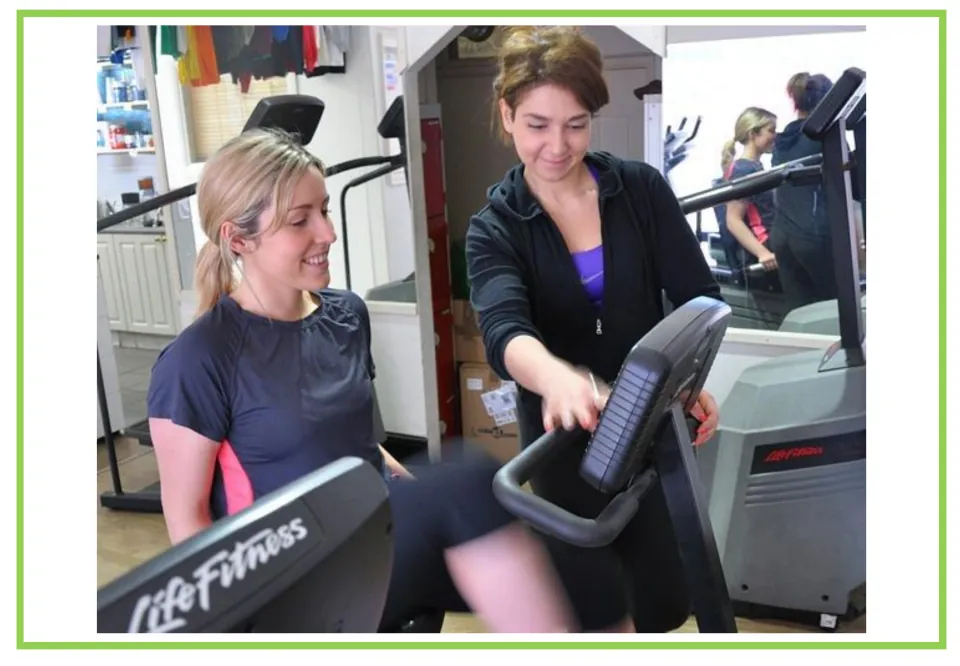 Picture-only gym vocabulary flashcard showing an instructor helping someone use an exercise machine