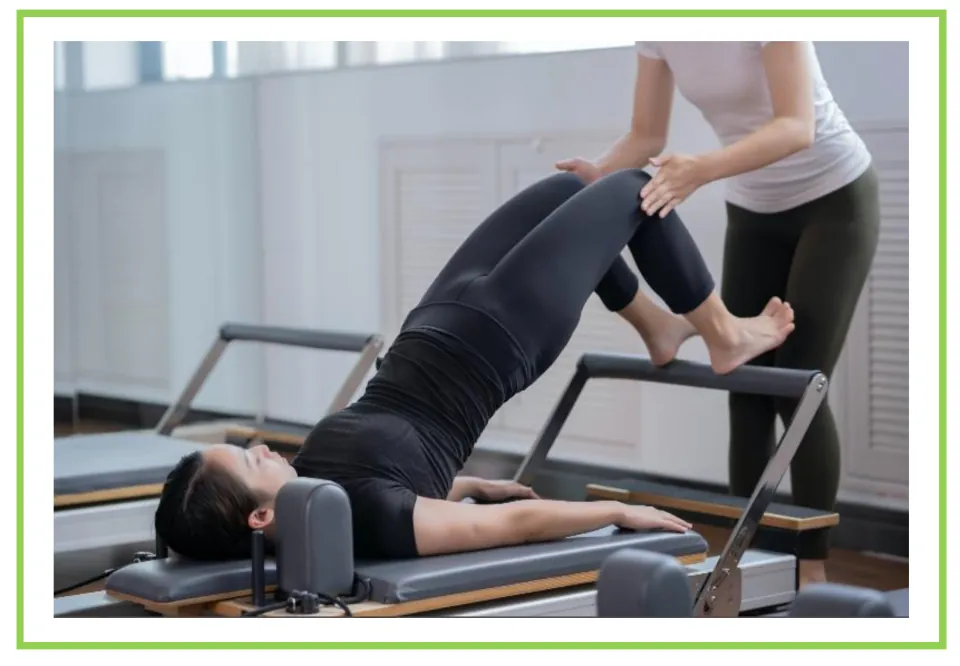 Picture-only gym vocabulary flashcard showing a person using a Pilates reformer with an instructor's help