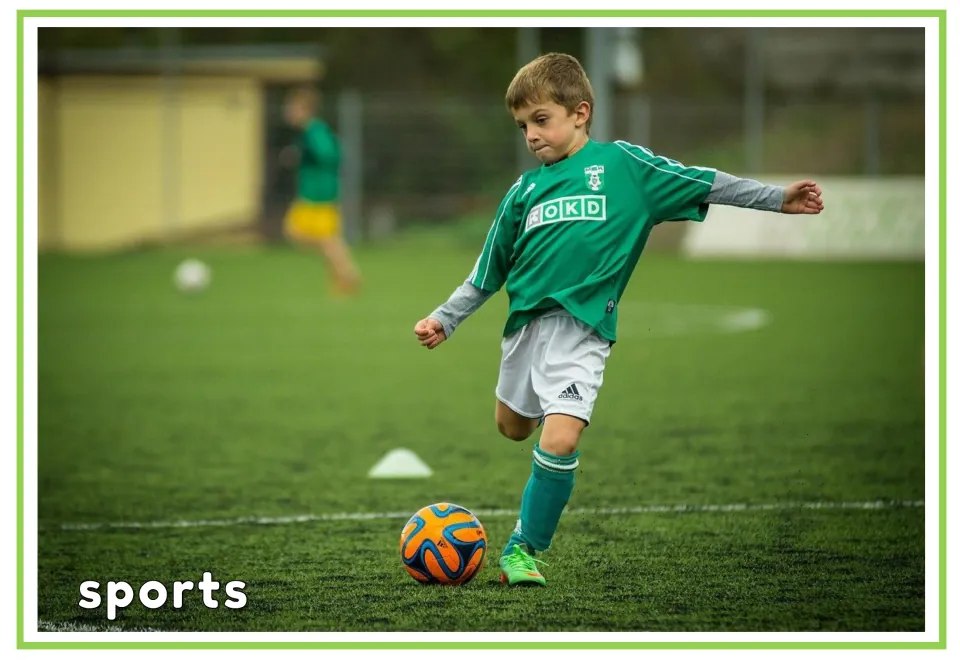 Labeled hobbies vocabulary flashcard showing a child kicking a soccer ball on a field, labeled 'sports'