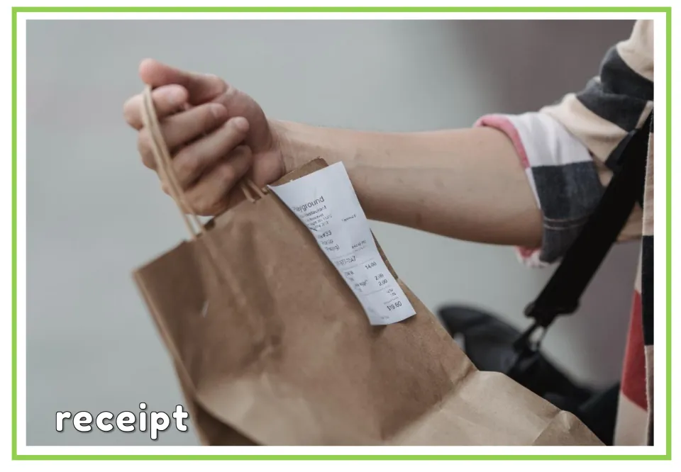 Labeled shopping vocabulary flashcard for 'receipt,' showing a printed receipt on a paper shopping bag