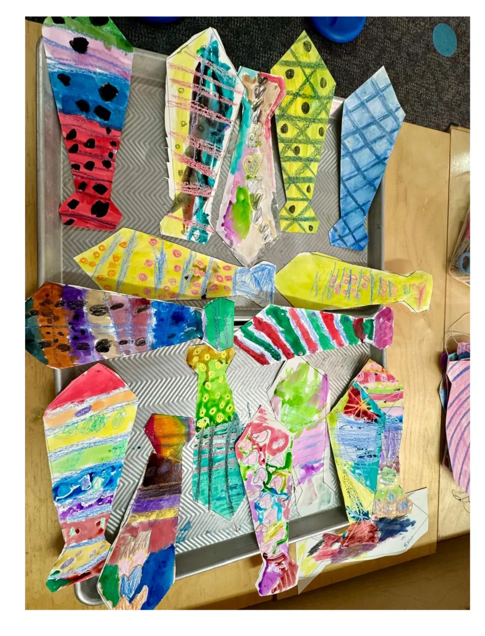 First student example sheet for the tie craft, showing watercolor ties decorated with stripes, dots and hearts
