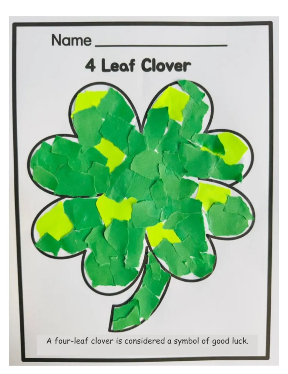 Finished clover craft example: the four-leaf clover outline covered in torn pieces of dark and light green paper