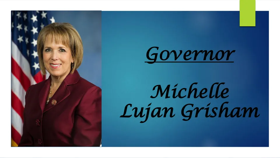Biography title slide introducing Governor Michelle Lujan Grisham, with her portrait beside a U.S. flag