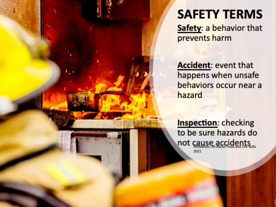 Safety terms slide defining safety, accident and inspection over a photo of a firefighter facing a stovetop fire
