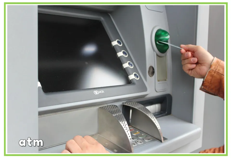 Labeled banking vocabulary flashcard showing a person inserting a card into an ATM, with the word "atm"