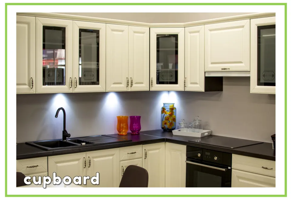 Labeled furniture vocabulary flashcard showing kitchen cupboards and a countertop with the word 'cupboard'