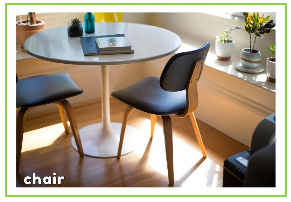 Labeled furniture vocabulary flashcard showing a chair with wooden legs beside a table and the word 'chair'