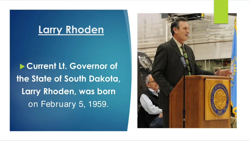 Biography slide giving Larry Rhoden’s birthdate as February 5, 1959, beside a photo of him at a podium