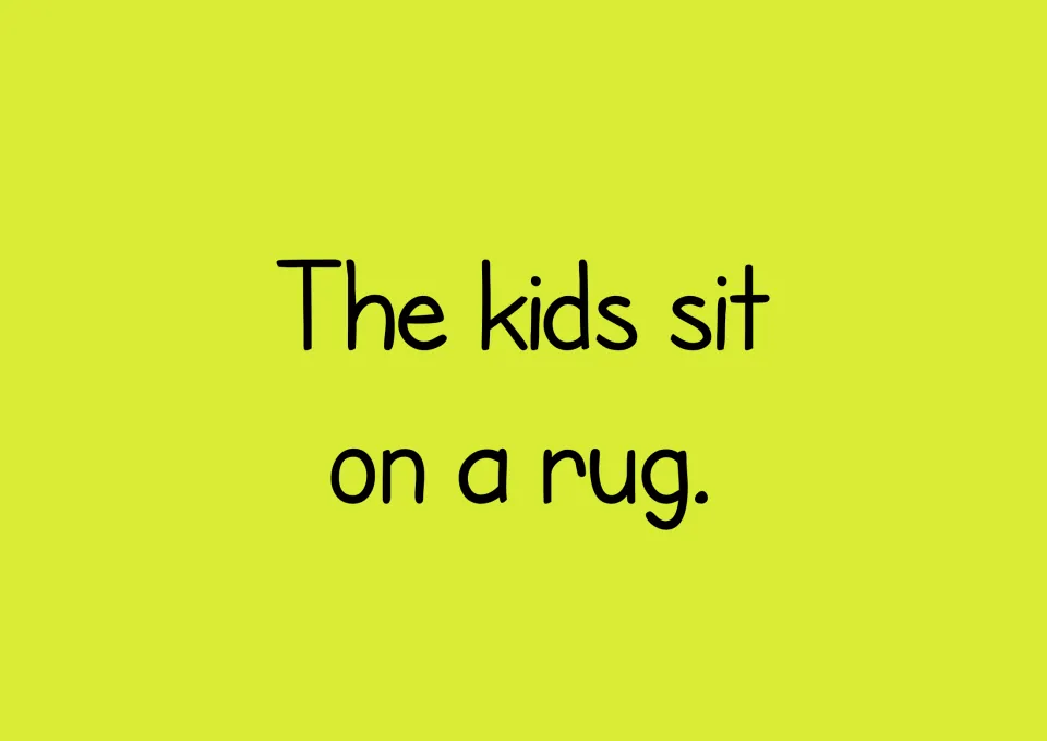 Reading sentence: The kids sit on a rug. Students read it, then build it from word cards in the sentence maker