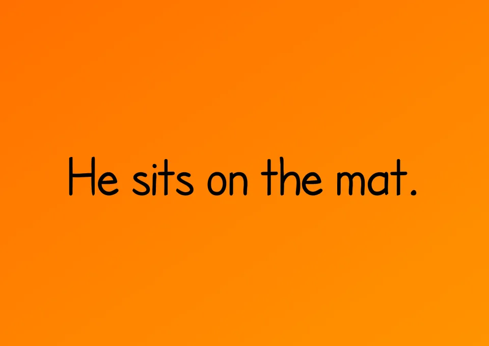 Story page with the sentence He sits on the mat. for students to read and copy using the word cards