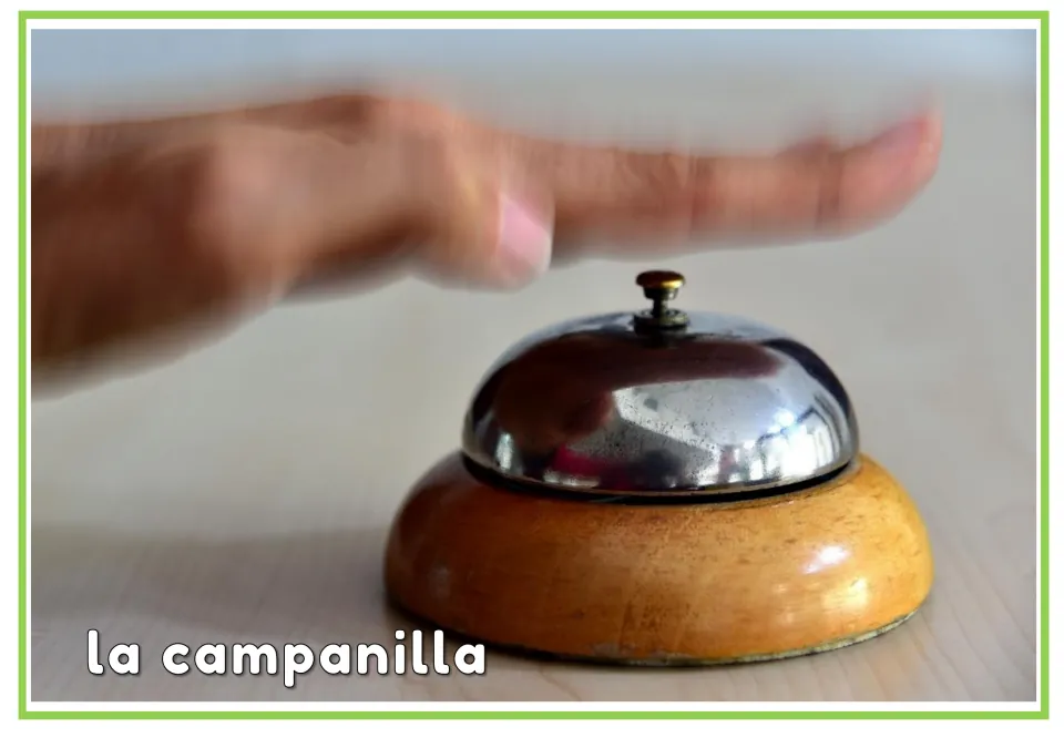 Spanish hotel vocabulary flashcard labeled 'la campanilla' (bell), showing a hand above a service bell