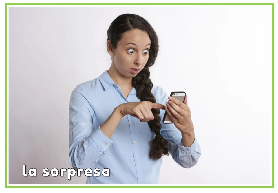 Spanish emotions flashcard labeled “la sorpresa” (surprise), showing a wide-eyed woman pointing at a phone