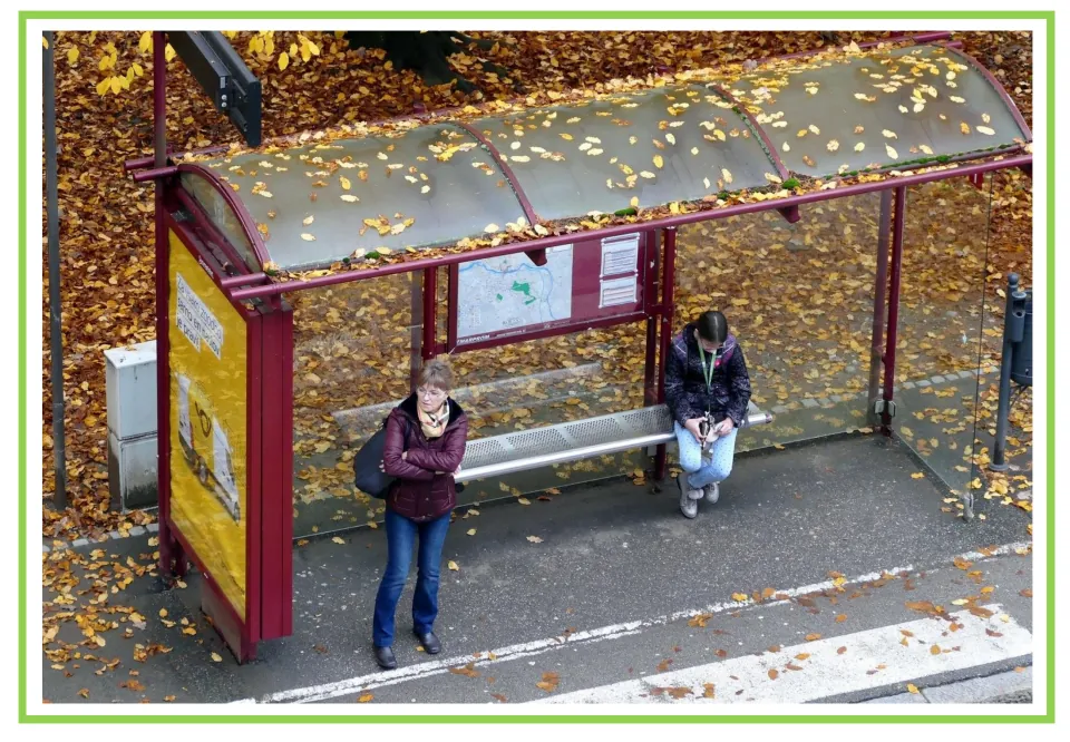 Unlabeled Spanish transportation flashcard showing people at a bus stop shelter, paired with the next card