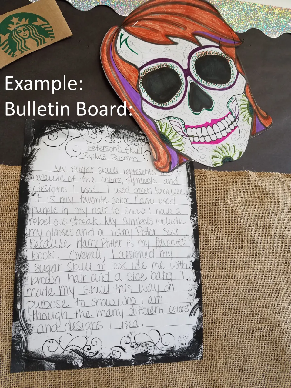Bulletin board example: a colored sugar skull with red hair and glasses beside a teacher's paragraph explaining its design