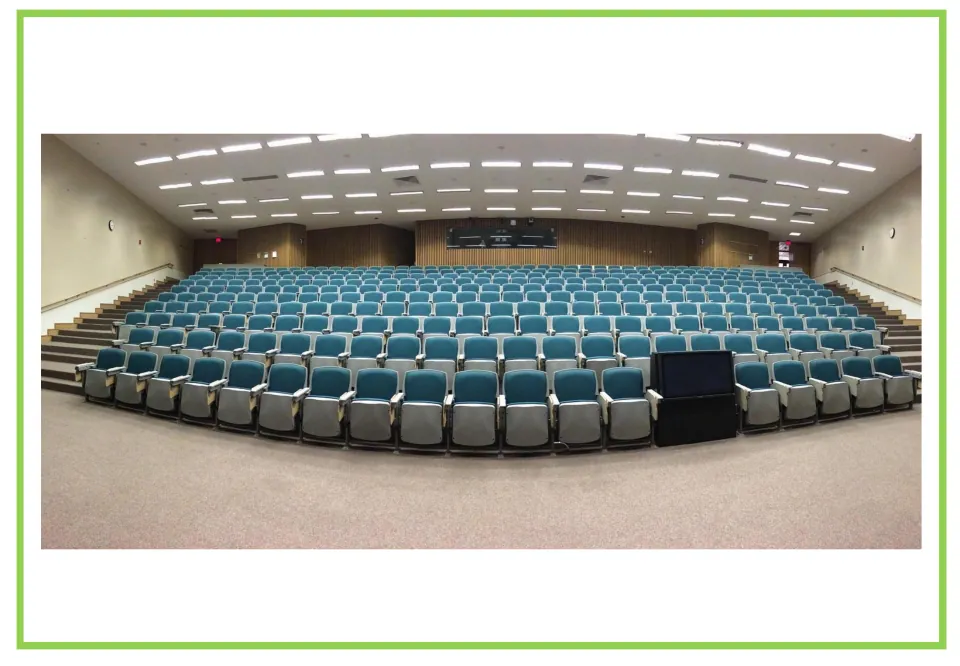Lecture hall flashcard: rows of empty teal seats rising toward the back of a large auditorium, a setting to describe