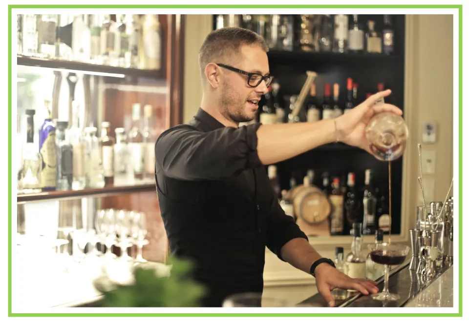 Bar and club discussion flashcard 4: a bartender pours liquid from a glass container behind the bar