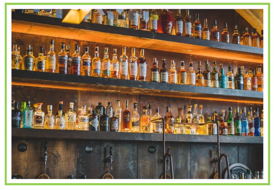 Bar and club discussion flashcard 6: shelves of liquor bottles displayed above drink taps at a bar