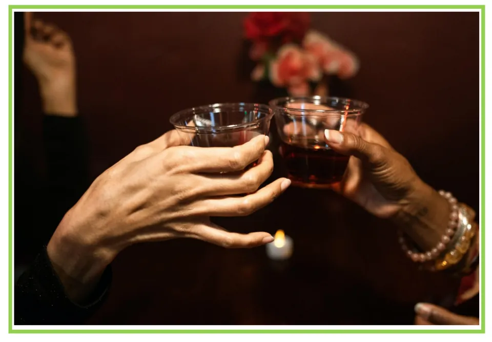 Bar and club discussion flashcard 8: two people touch their glasses of dark drinks together in a toast