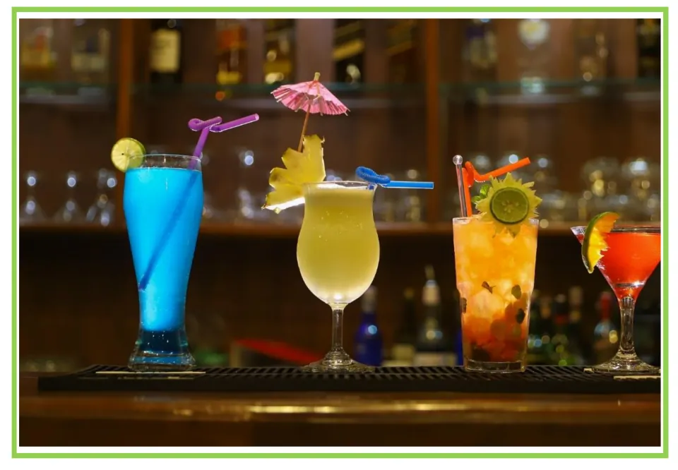 Bar and club discussion flashcard 10: four colorful cocktails with fruit garnishes lined up on a bar