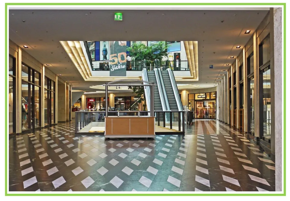 Building discussion and writing prompt card 4: a shopping mall interior with escalators and storefronts