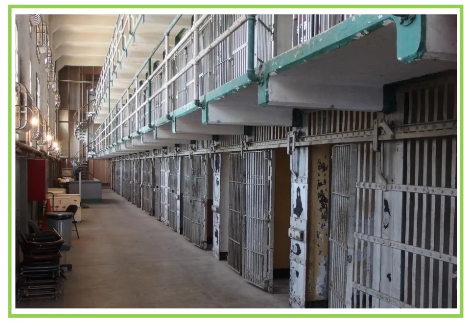 Building discussion and writing prompt card 7: a prison interior with barred cell doors and an upper walkway