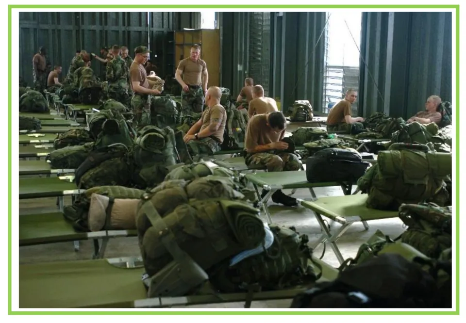 Building discussion and writing prompt card 9: military personnel among rows of cots and packed equipment