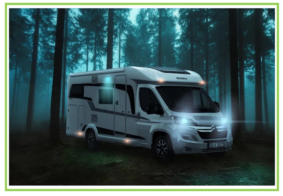 Camping writing and discussion prompt card 4: a white motorhome parked among tall trees with its lights on