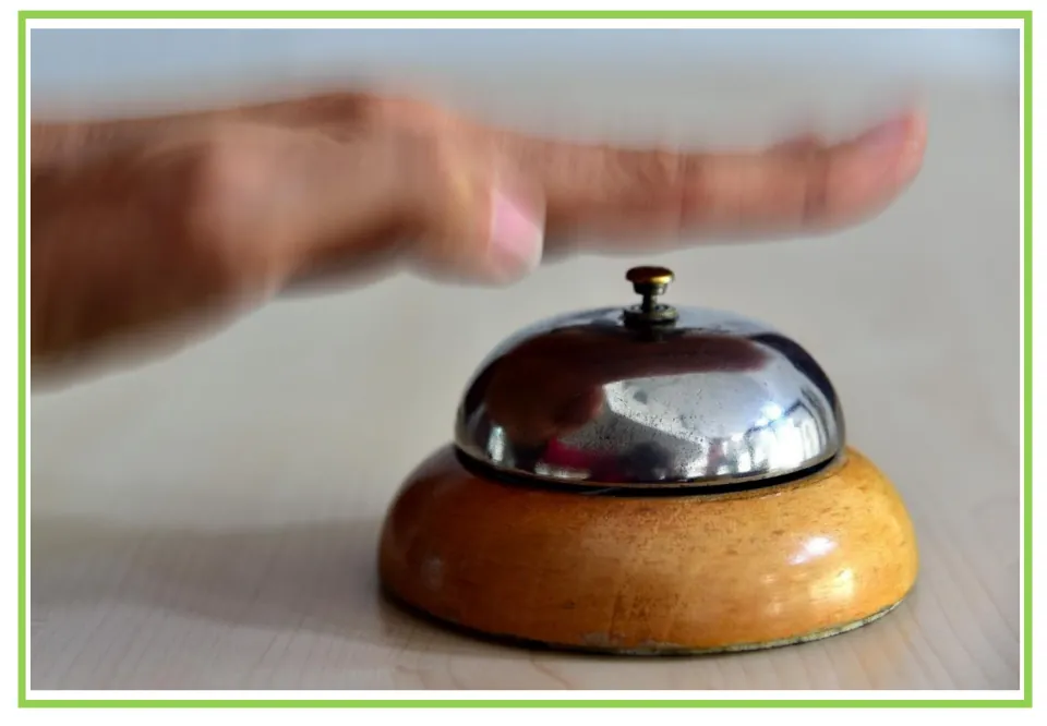 Hotel writing and discussion flashcard 3: a hand reaches toward the button on a metal service bell
