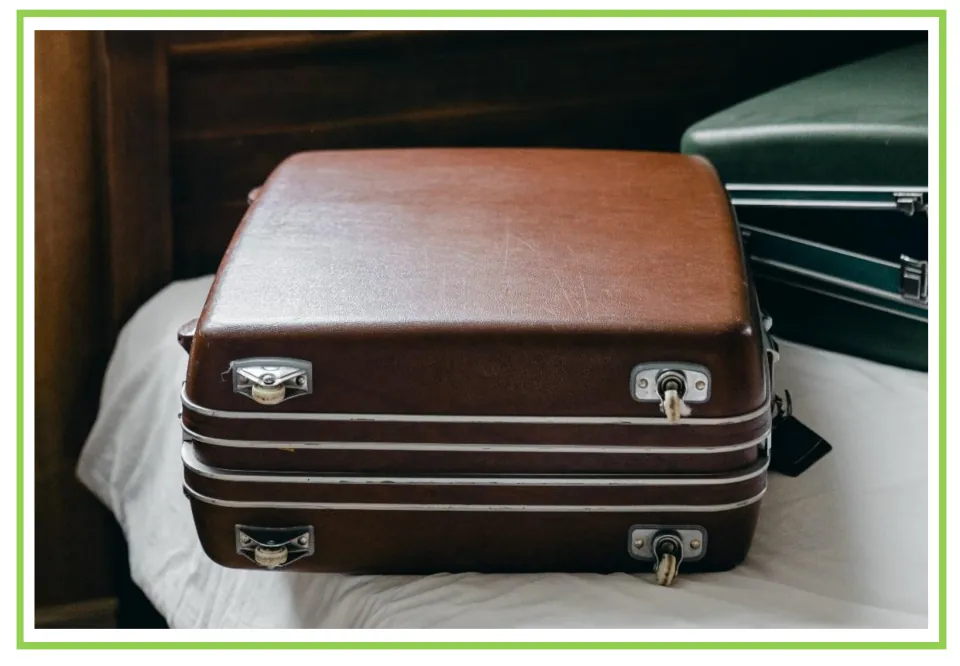 Hotel writing and discussion flashcard 4: a closed brown suitcase rests on a bed beside a green suitcase