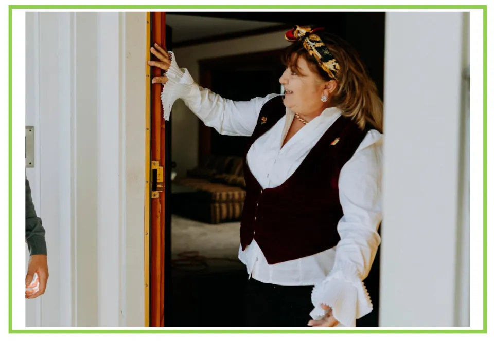 Party writing and discussion flashcard 3: a person in a white ruffled shirt and dark vest at an open door