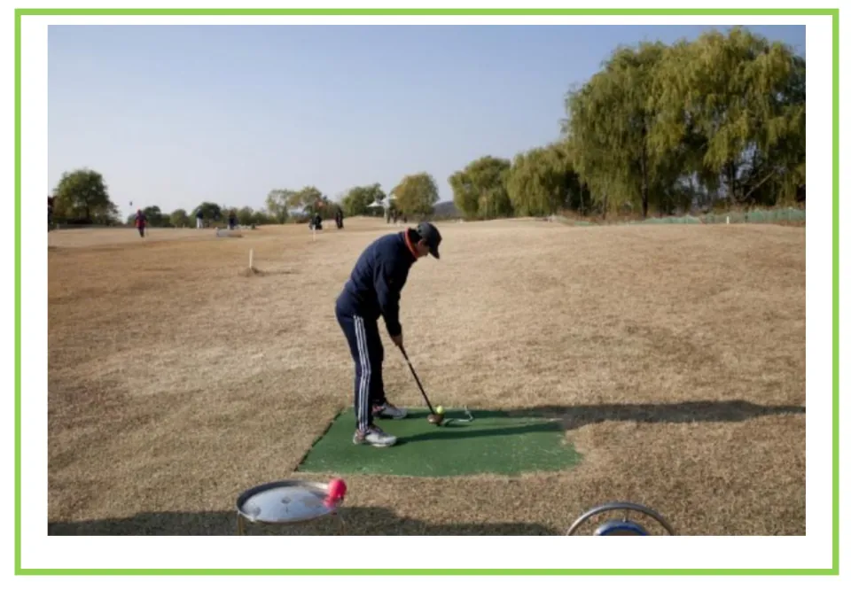 Golf writing and discussion flashcard showing a golfer preparing to hit a ball from a mat on an outdoor range