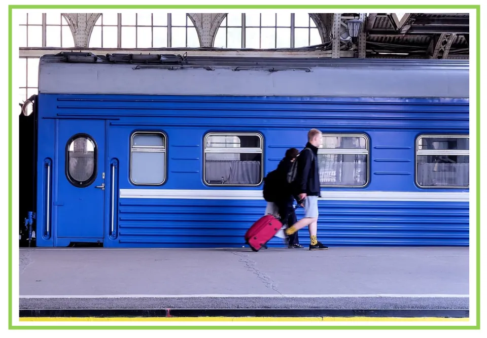 Train writing and discussion prompt card 2: travelers walking beside a blue train with rolling luggage