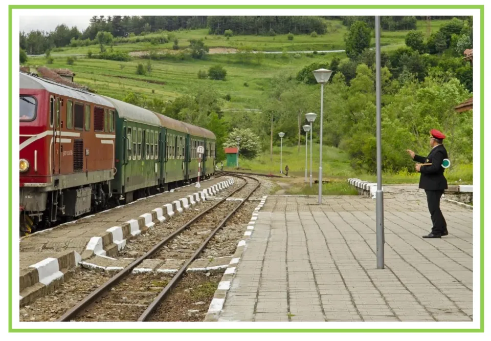 Train writing and discussion prompt card 8: a uniformed railway worker signaling beside a passenger train